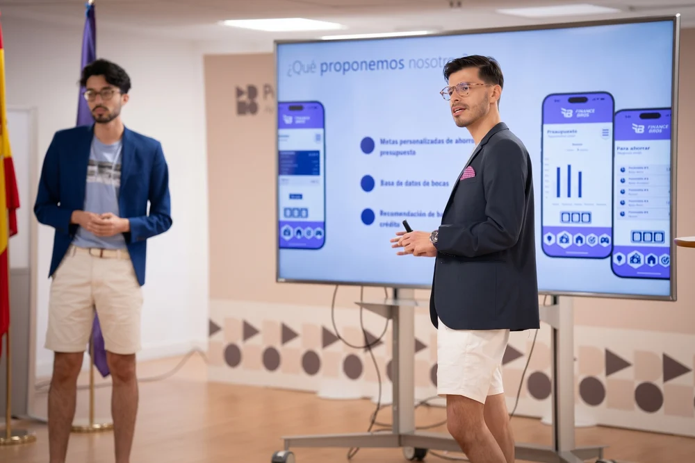 Julián y Mario presentando en el escenario de los Santander X Award, vestidos con shorts, camiseta y americana.